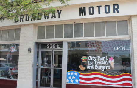 city-point-ice-cream-burgers → Visit Hopewell / Prince George VA → Visit Hopewell / Prince George VA Storefront with a large 'Broadway Motor' sign, glass doors, and an 'OPEN' sign; window graphics advertise City Point Ice Cream and Burgers with an American flag illustration.